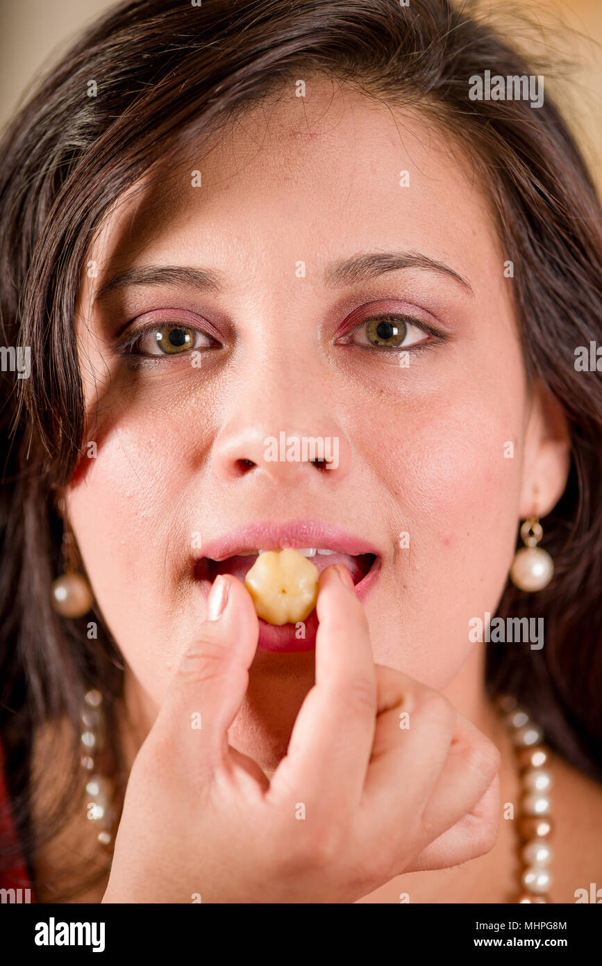 Portrait of woman wearing a pink blouse and eating a star gooseberry fruit. Phyllanthus acidus, known as the Otaheite gooseberry, star, damsel, grosella, karamay Stock Photo