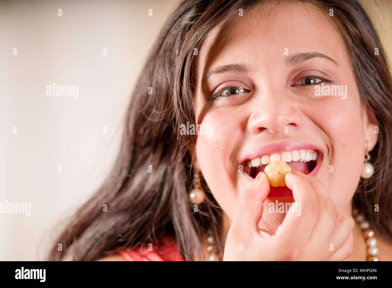 Portrait of woman wearing a pink blouse and eating a star gooseberry fruit. Phyllanthus acidus, known as the Otaheite gooseberry, star, damsel, grosella, karamay Stock Photo