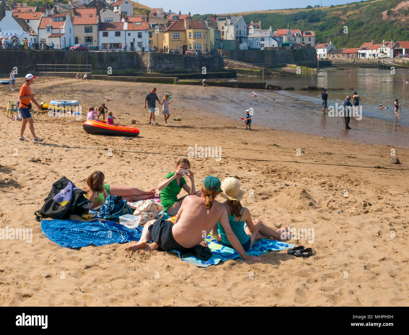 Holiday makers on the beach in the harbour at Staithes North Yorkshire UK on a hot day in summer Stock Photo