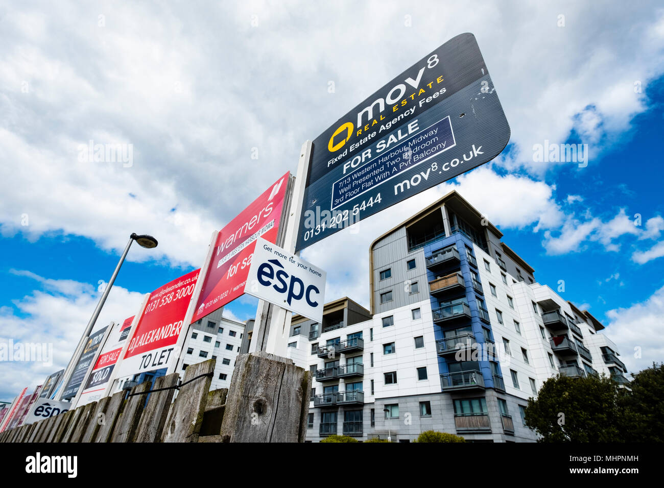 Many sign boards from estate agents for properties for sale and rent outside large modern apartment blocks at western Harbour in Leith, Edinburgh, Sco Stock Photo