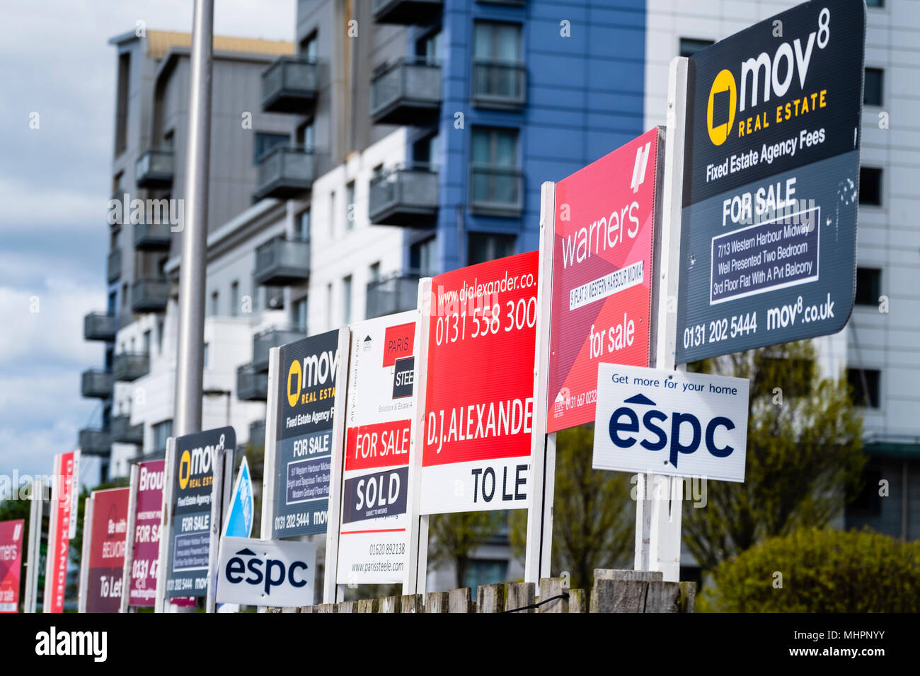 Many sign boards from estate agents for properties for sale and rent outside large modern apartment blocks at western Harbour in Leith, Edinburgh, Sco Stock Photo
