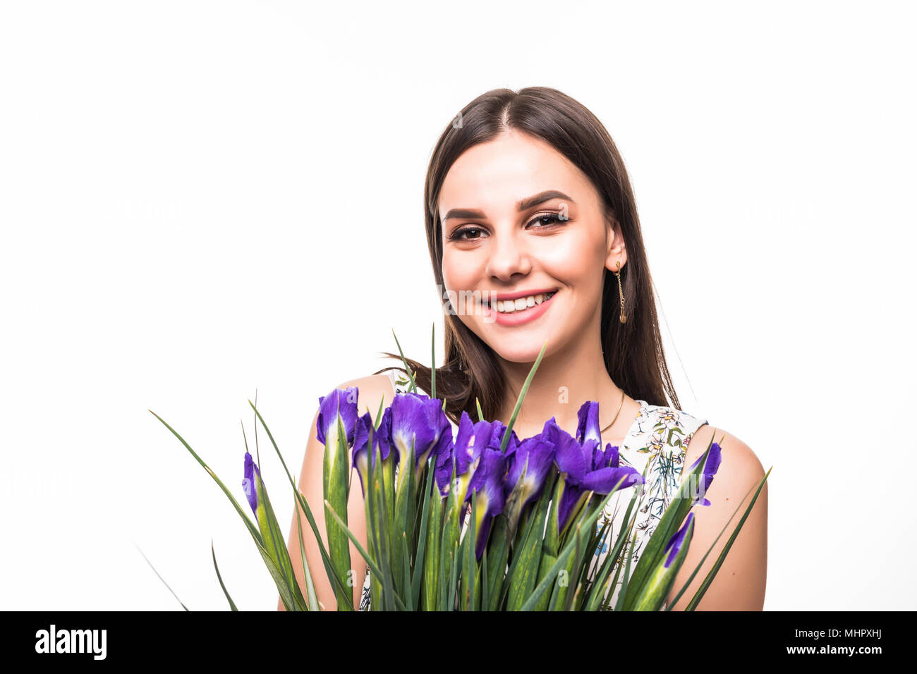 attractive young woman in dress holding iris flowers and looking at ...