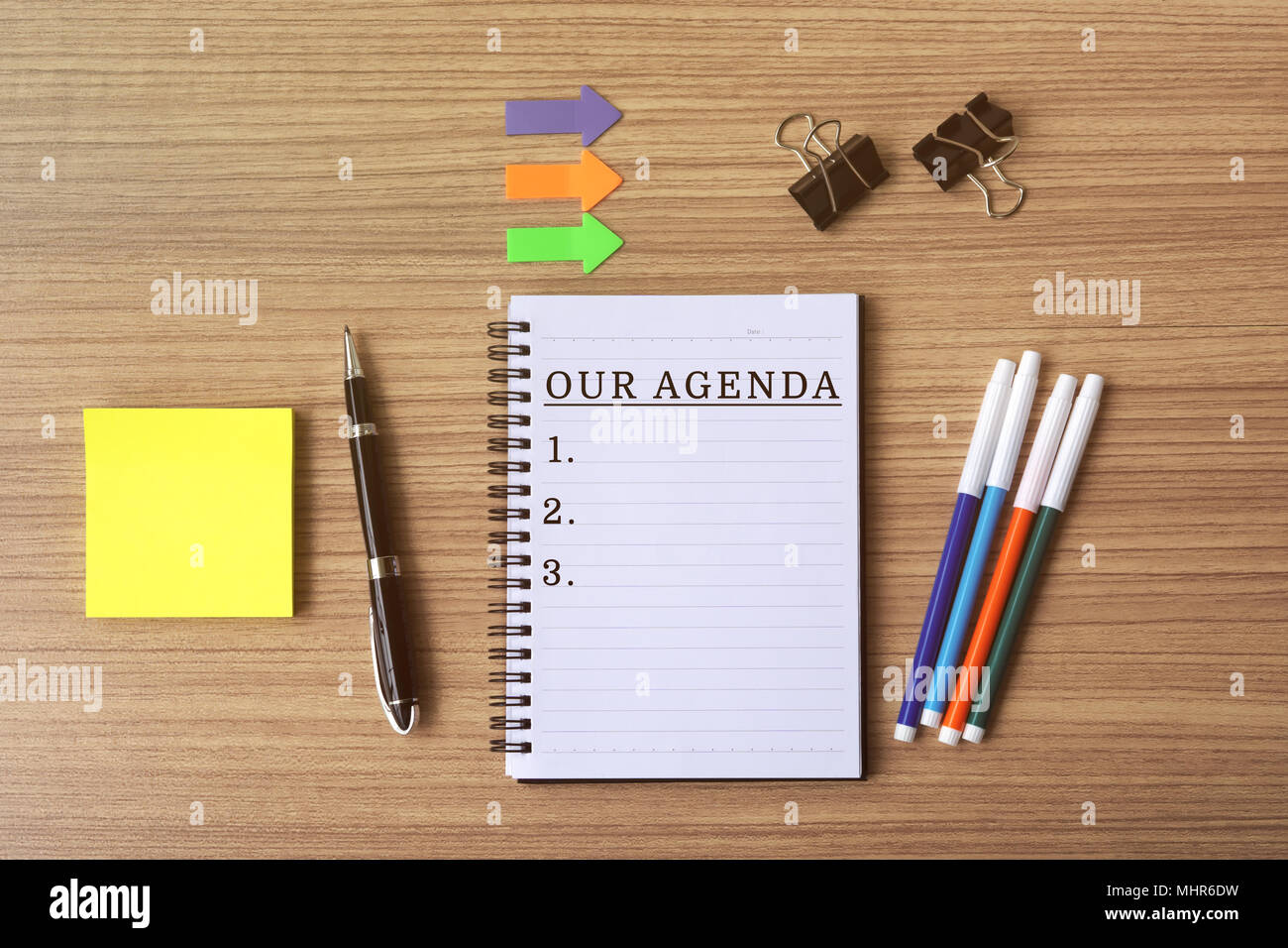 Our agenda list text on notepad, flat lay business office desk. Stock Photo