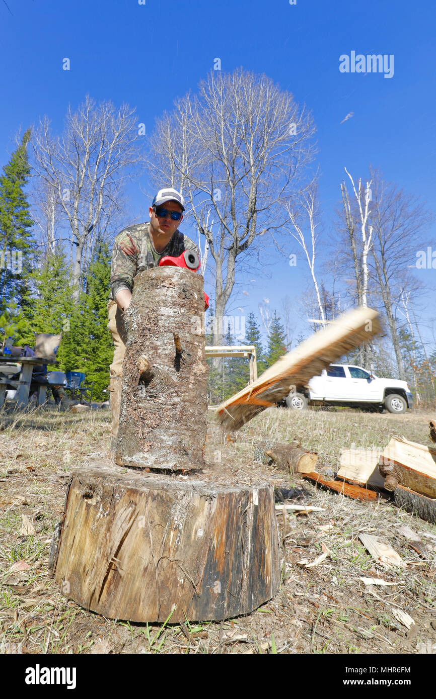 Firewood being split by a man with an ax. Stock Photo