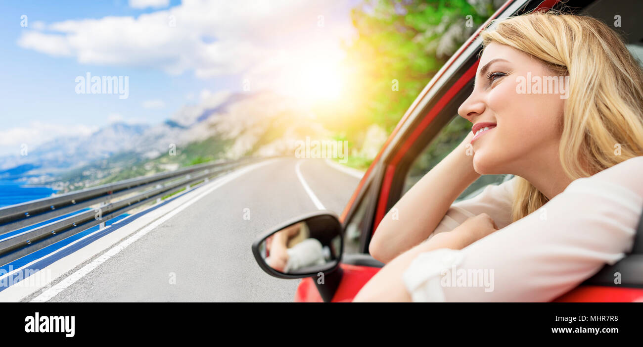 Travel or vacation. Beautiful blond girl in car on the road to the sea. Stock Photo