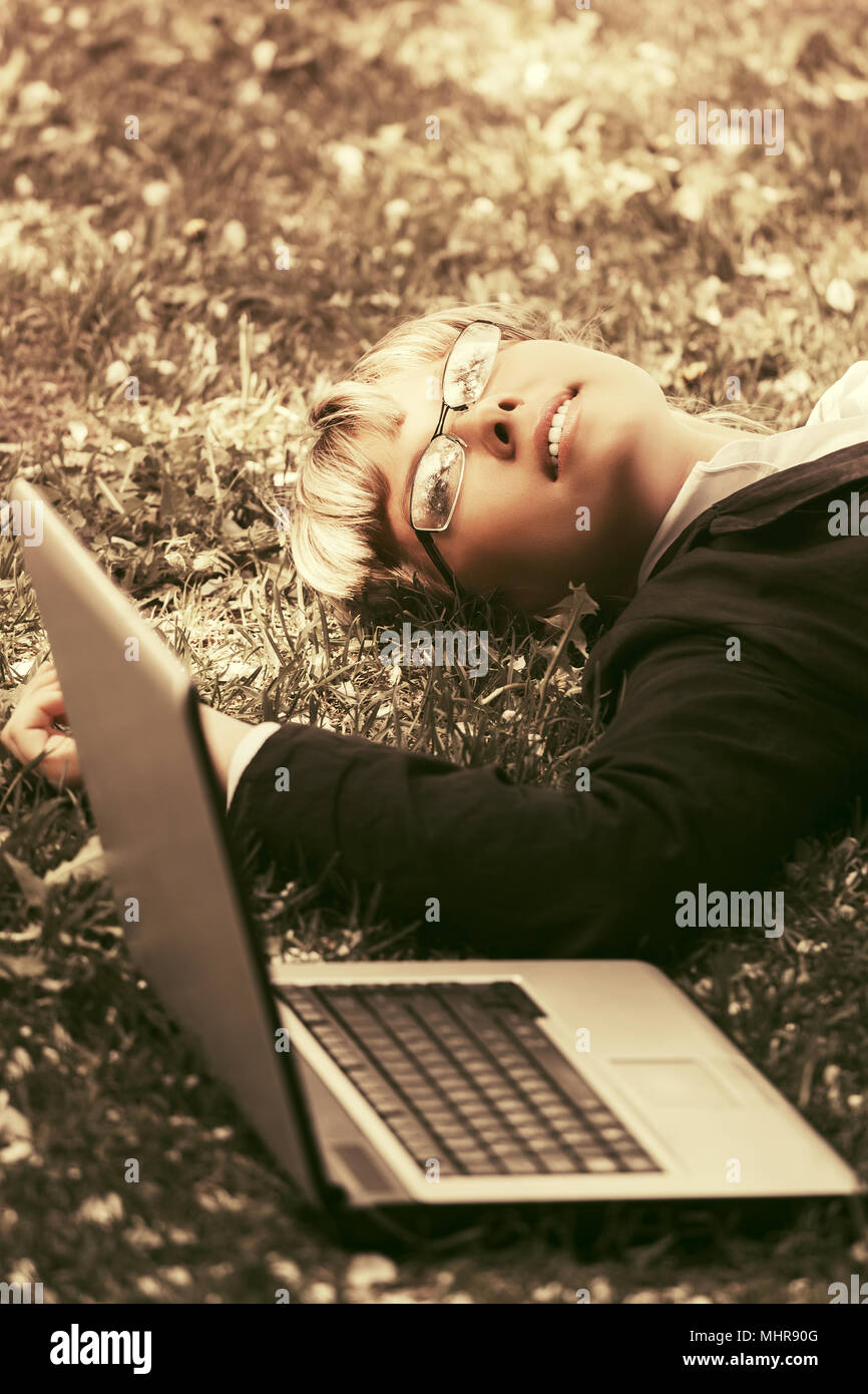Happy business woman with laptop lying on the grass Stock Photo - Alamy