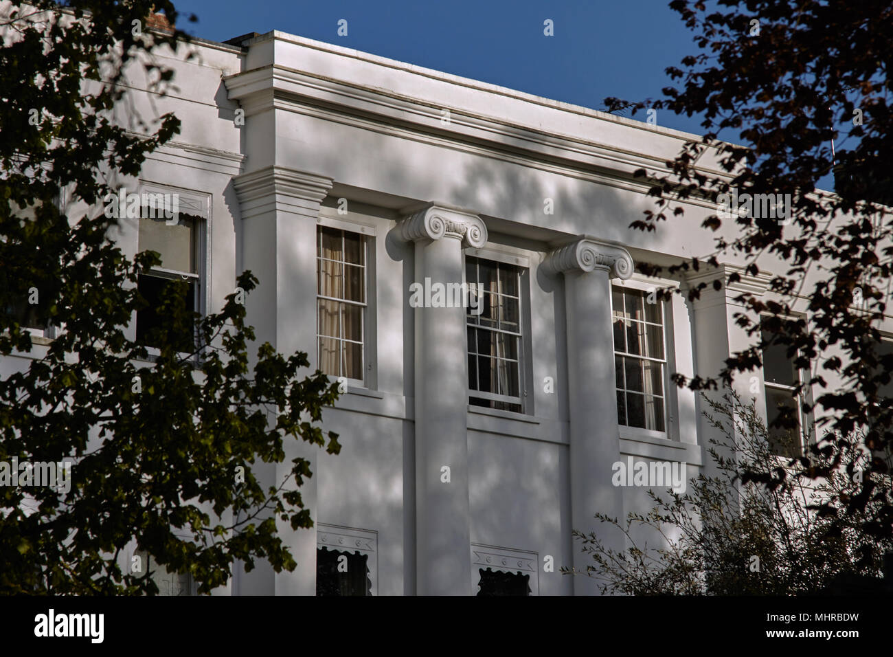 Dappled light during sunset on the upper storey and sash windows of a regency property in Cheltenham. Stock Photo