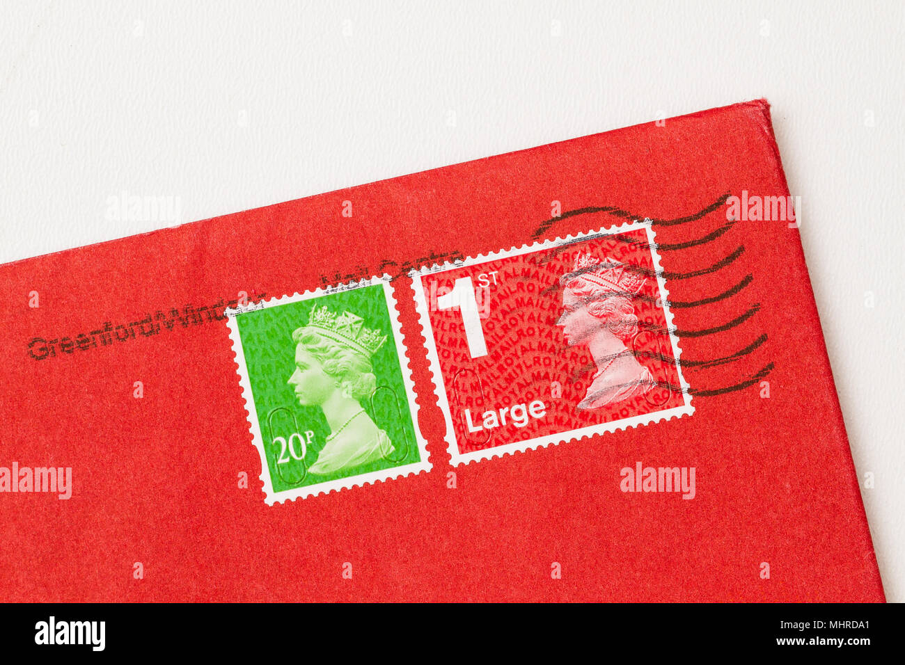Envelope corner with 2 stamps, ones red, one green, of Queen Elisabeth II. UK postage stamp on red paper. Stock Photo