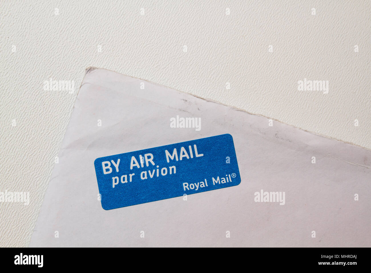 White envelope corner. By air mail par avion by Royal Mail. By plane blue with white stamp, on the corner of an envelope, isolated on white. Stock Photo