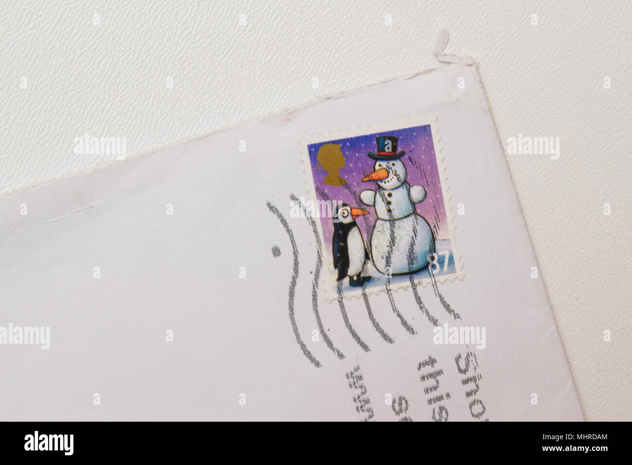 Colorful Christmas stamp. Snowman and penguin stamp close-up. Corner of white british envelope isolated on white background. Winter illustration stamp Stock Photo