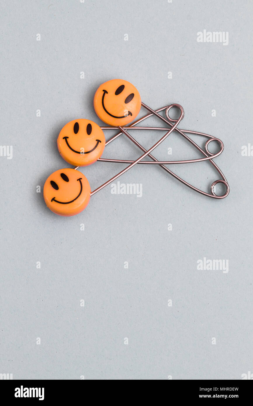 Plastic head metal safety pins pinned in light grey paper. Orange