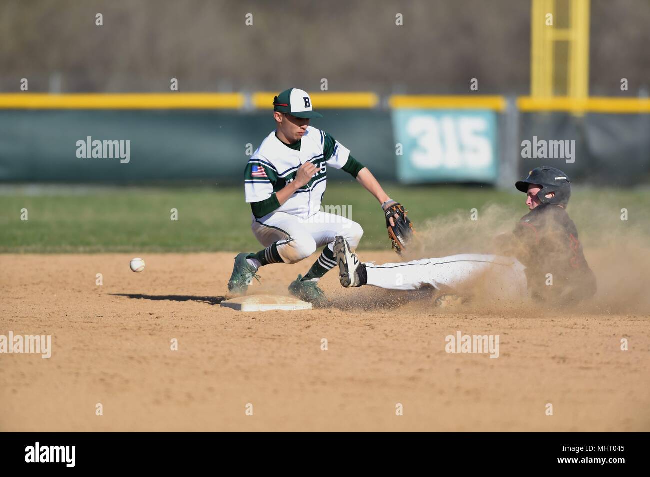 A second baseman was unable to handle the throw from right field as the opposing team's runner slid in safely. USA. Stock Photo
