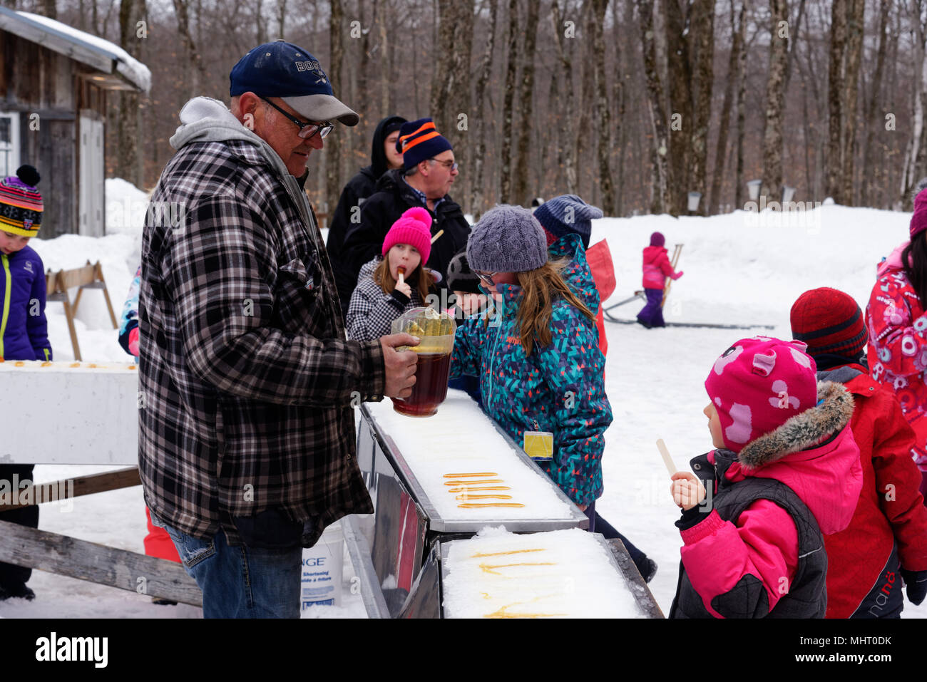 Children eating maple syrup taffy poured on ice at a sugar shack in Quebec,  Canada Stock Photo - Alamy