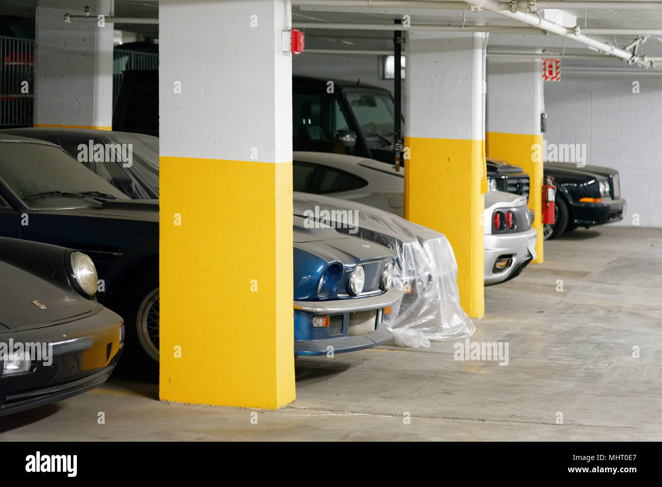 Expensive luxury cars in an underground car park in Montreal Quebec. They are covered in dust as they have not been used in years. Stock Photo