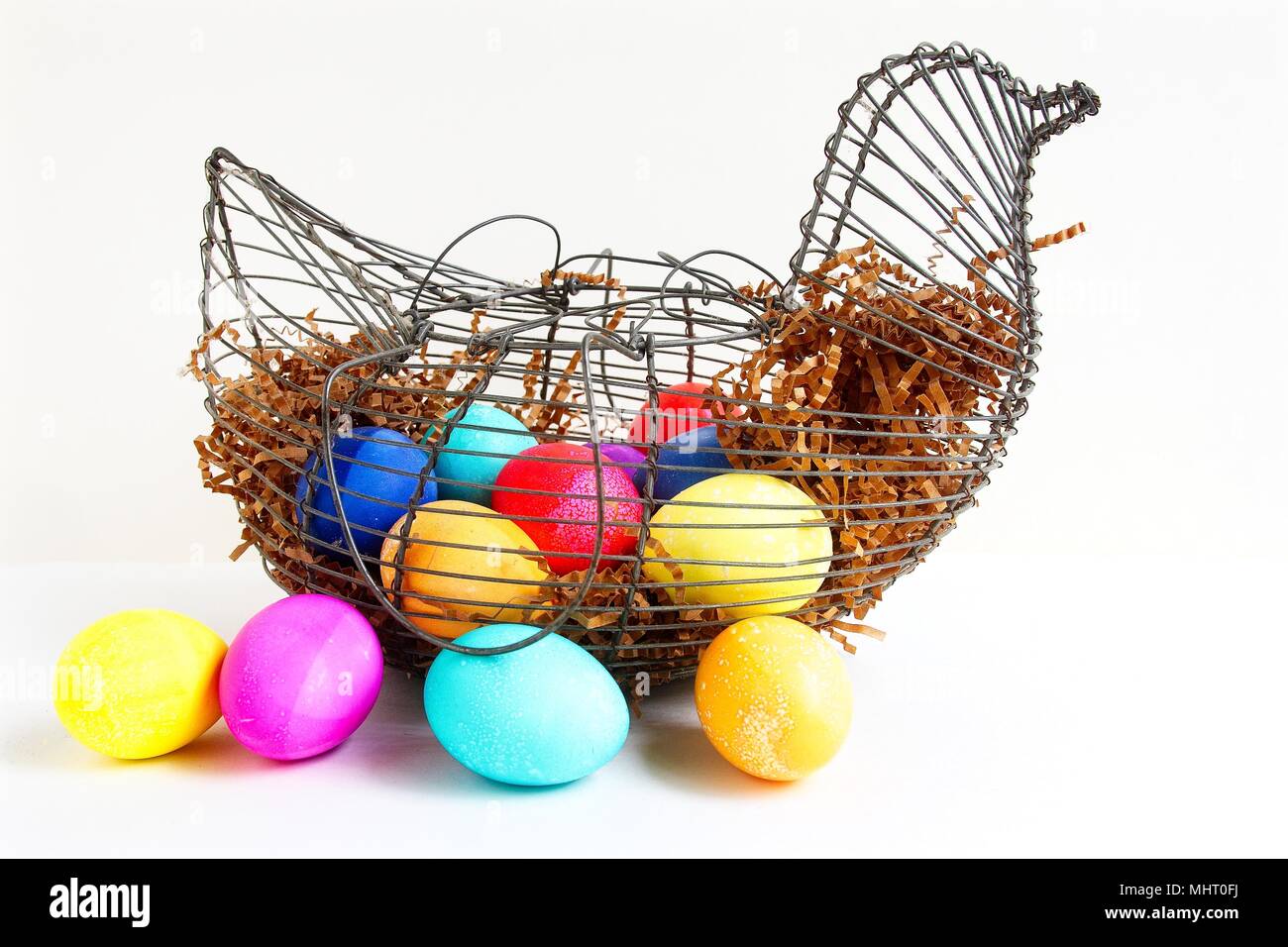 Colored eggs in a wire chicken basket, isolated on a white background Stock Photo