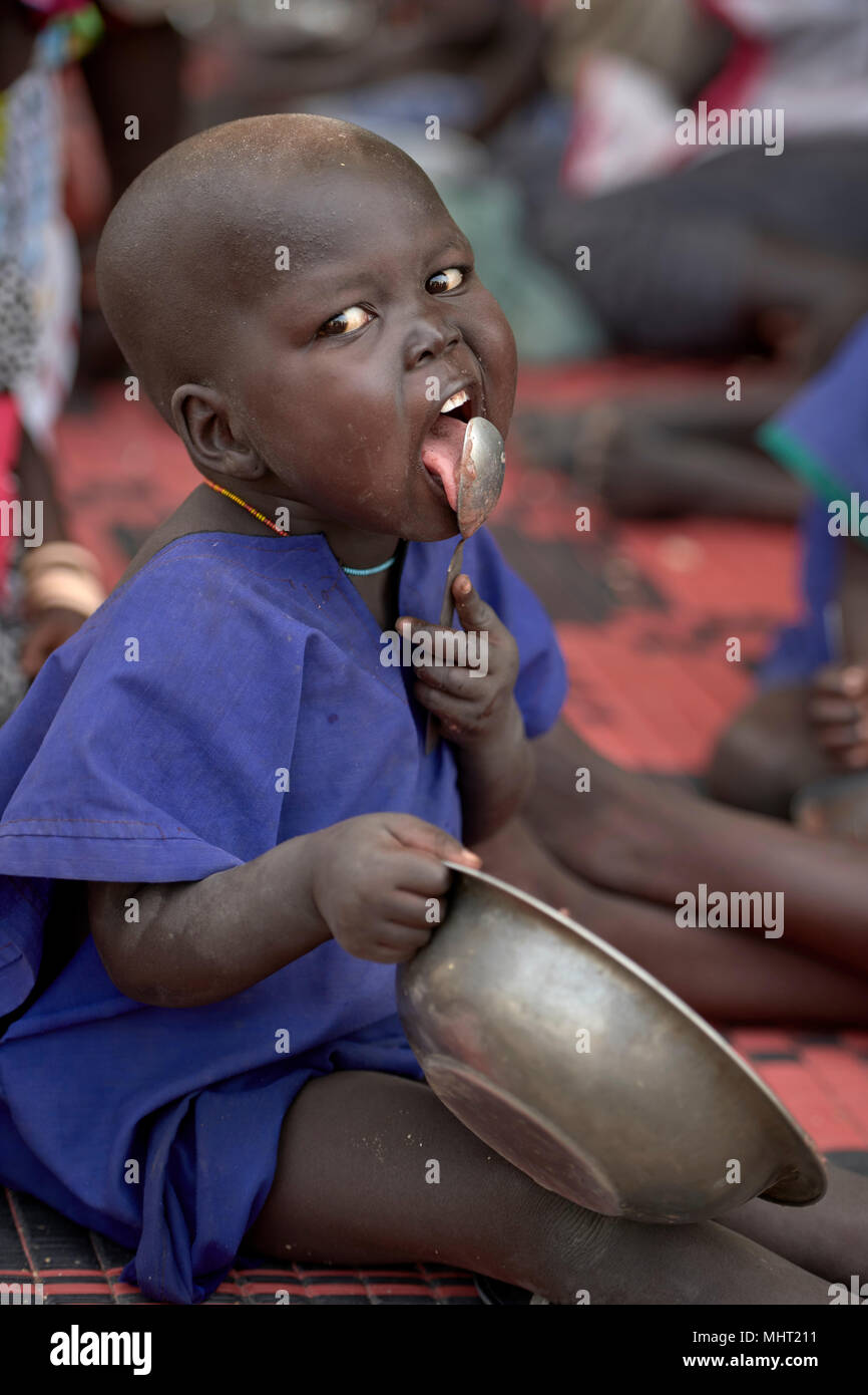 A child relishes the last of their food in an emergency feeding program for malnourished children at the Loreto Girls School in Rumbek, South Sudan. Stock Photo