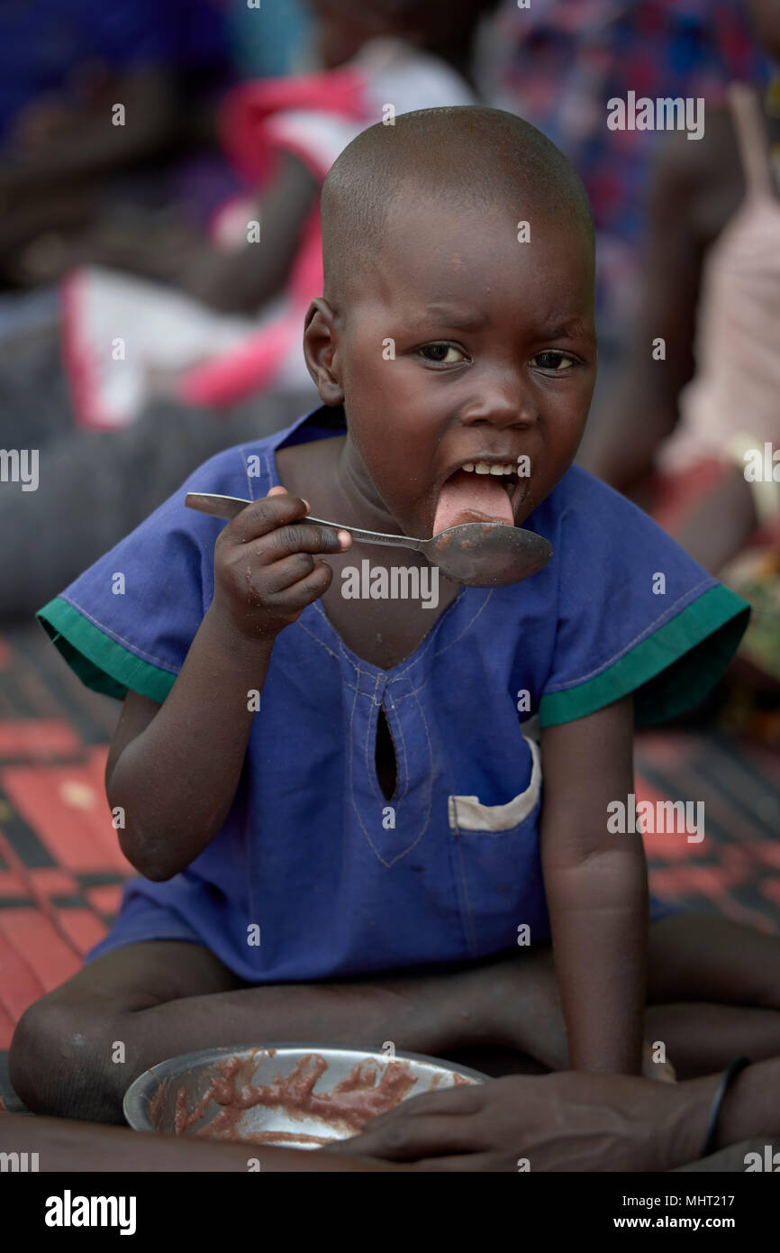 A child relishes the last of their food in an emergency feeding program for malnourished children at the Loreto Girls School in Rumbek, South Sudan. Stock Photo