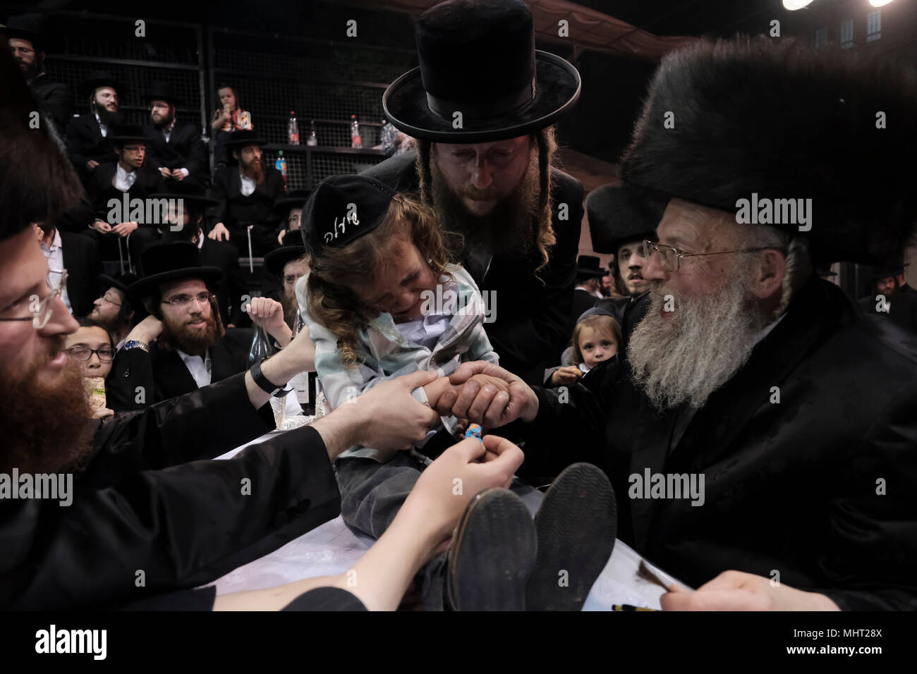 A three-year old Jewish boy takes part in the traditional Halake ceremony, a first hair cut from the Rabbi of the Pinsk-Karlin Hassidic dynasty in Geula religious neighborhood during the celebration of Lag BaOmer holiday which marks the celebration, interpreted by some as anniversary of death of Rabbi Shimon bar Yochai, one of Judaism's great sages some 1800 years ago and the day on which he revealed the deepest secrets of kabbalah a landmark text of Jewish mysticism Stock Photo