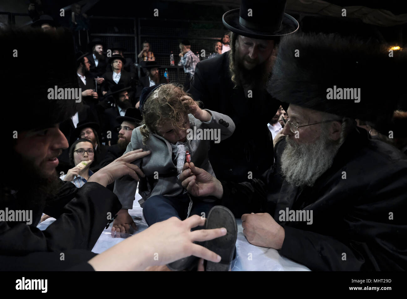 A three-year old Jewish boy takes part in the traditional Halake ceremony, a first hair cut from the Rabbi of the Pinsk-Karlin Hassidic dynasty in Geula religious neighborhood during the celebration of Lag BaOmer holiday which marks the celebration, interpreted by some as anniversary of death of Rabbi Shimon bar Yochai, one of Judaism's great sages some 1800 years ago and the day on which he revealed the deepest secrets of kabbalah a landmark text of Jewish mysticism Stock Photo