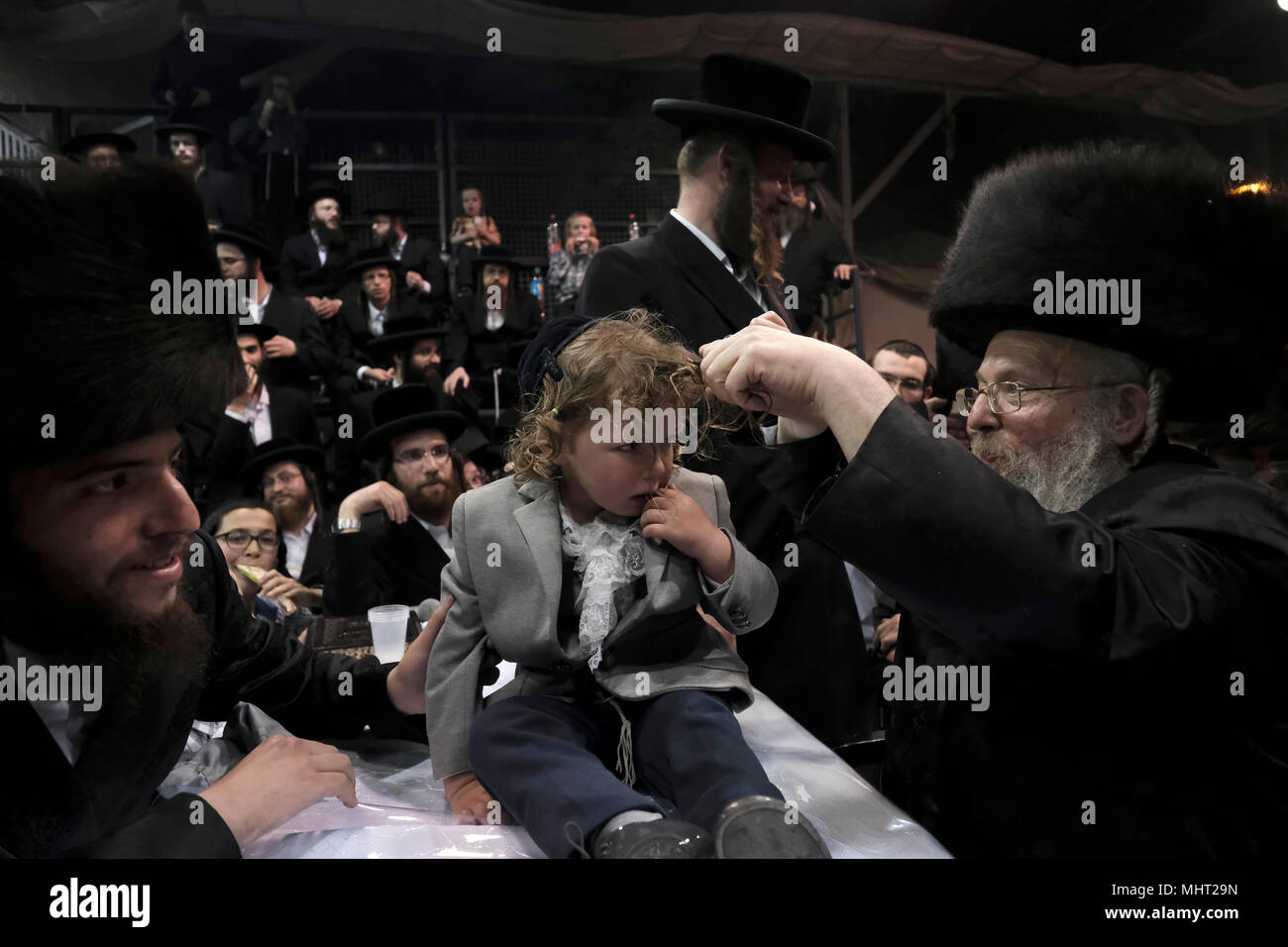 A three-year old Jewish boy takes part in the traditional Halake ceremony, a first hair cut from the Rabbi of the Pinsk-Karlin Hassidic dynasty in Geula religious neighborhood during the celebration of Lag BaOmer holiday which marks the celebration, interpreted by some as anniversary of death of Rabbi Shimon bar Yochai, one of Judaism's great sages some 1800 years ago and the day on which he revealed the deepest secrets of kabbalah a landmark text of Jewish mysticism Stock Photo