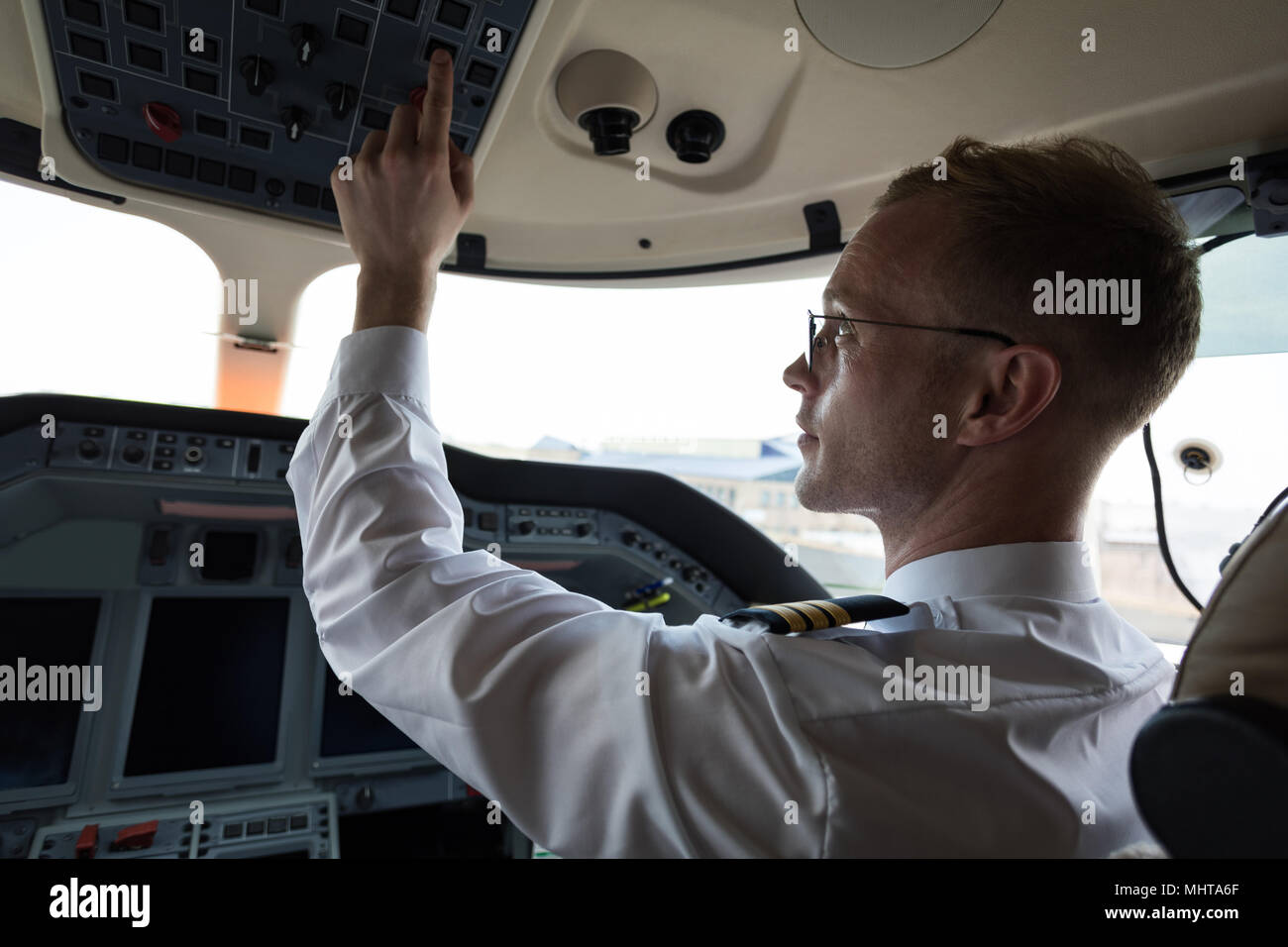 Male pilot pushing button in cockpit Stock Photo