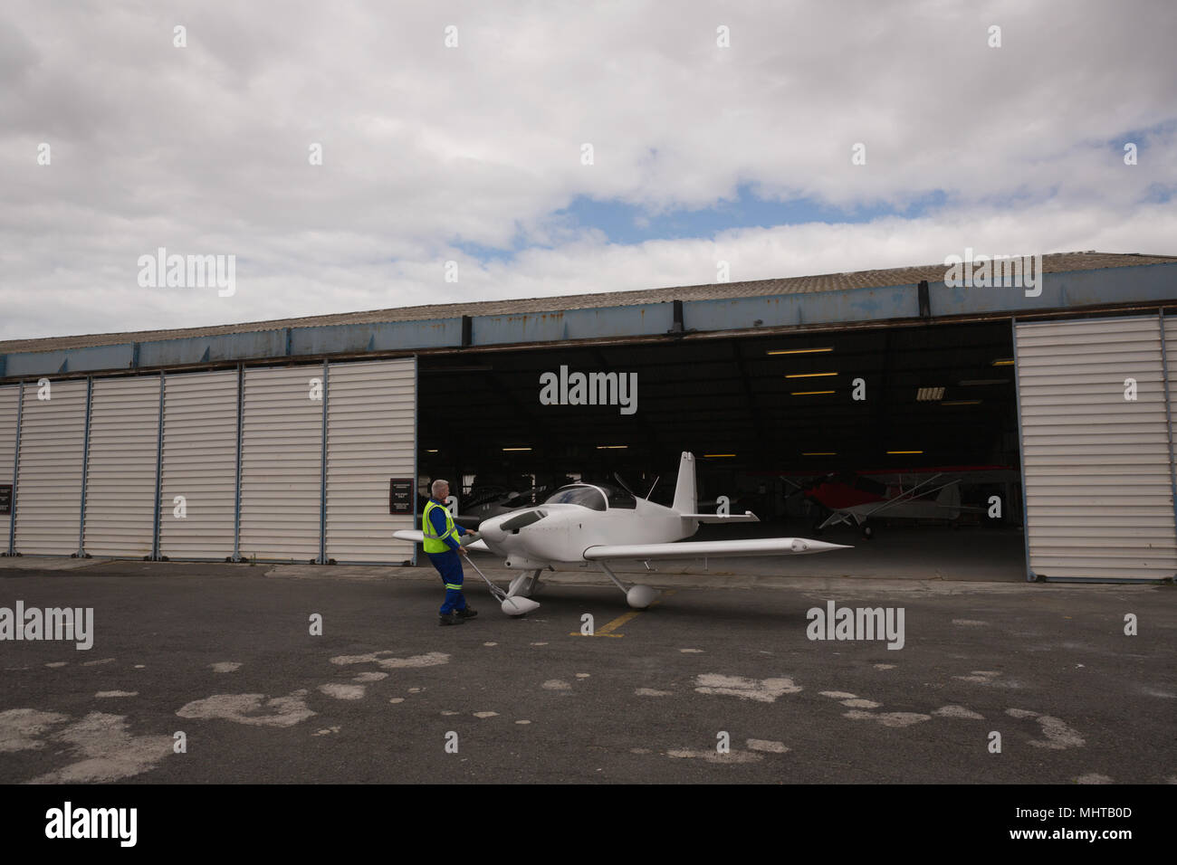 Crew member taking out aircraft from hangar Stock Photo