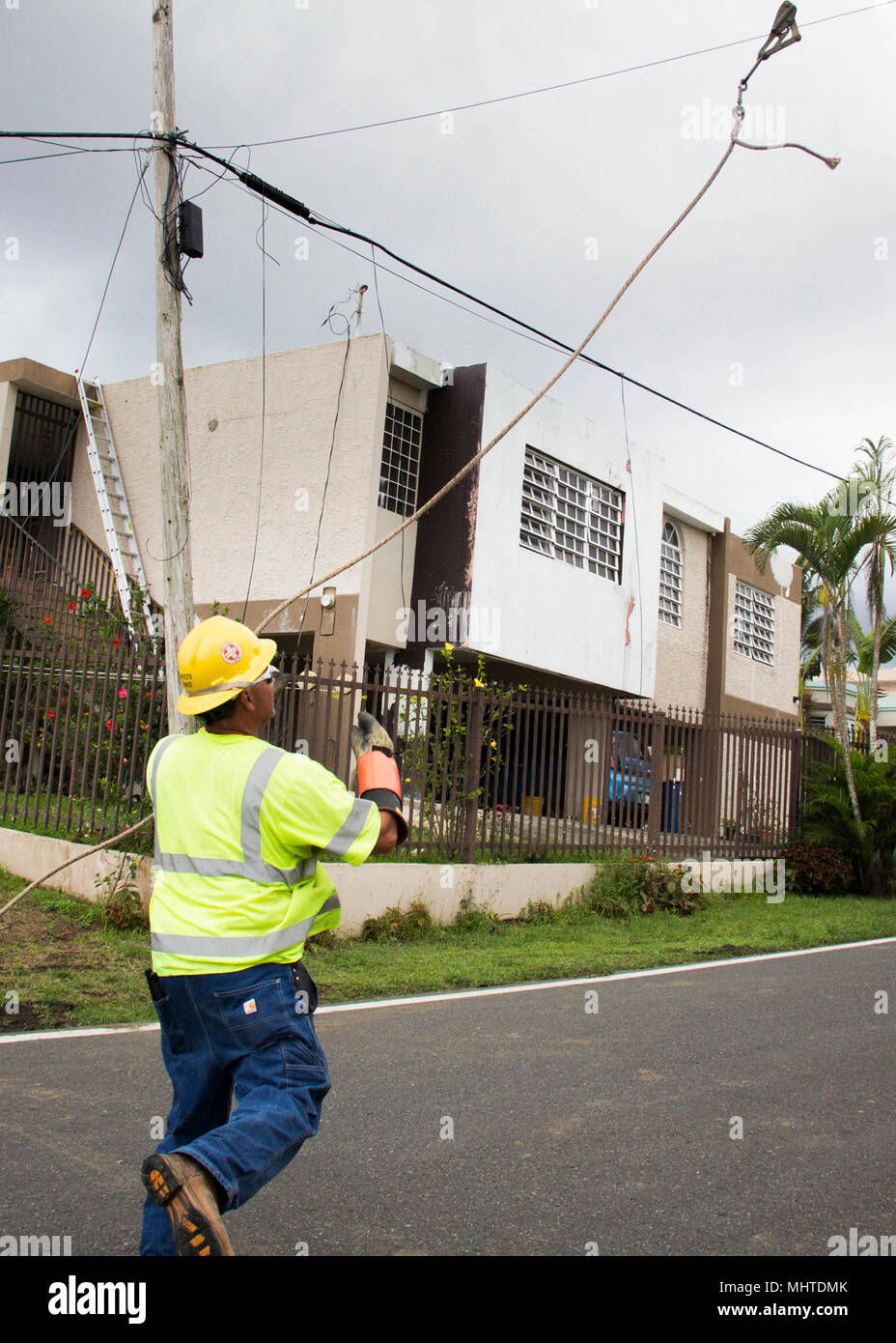 Line Workers Riding Wire A line worker tosses a guide rope over an existing cable. He will use ...