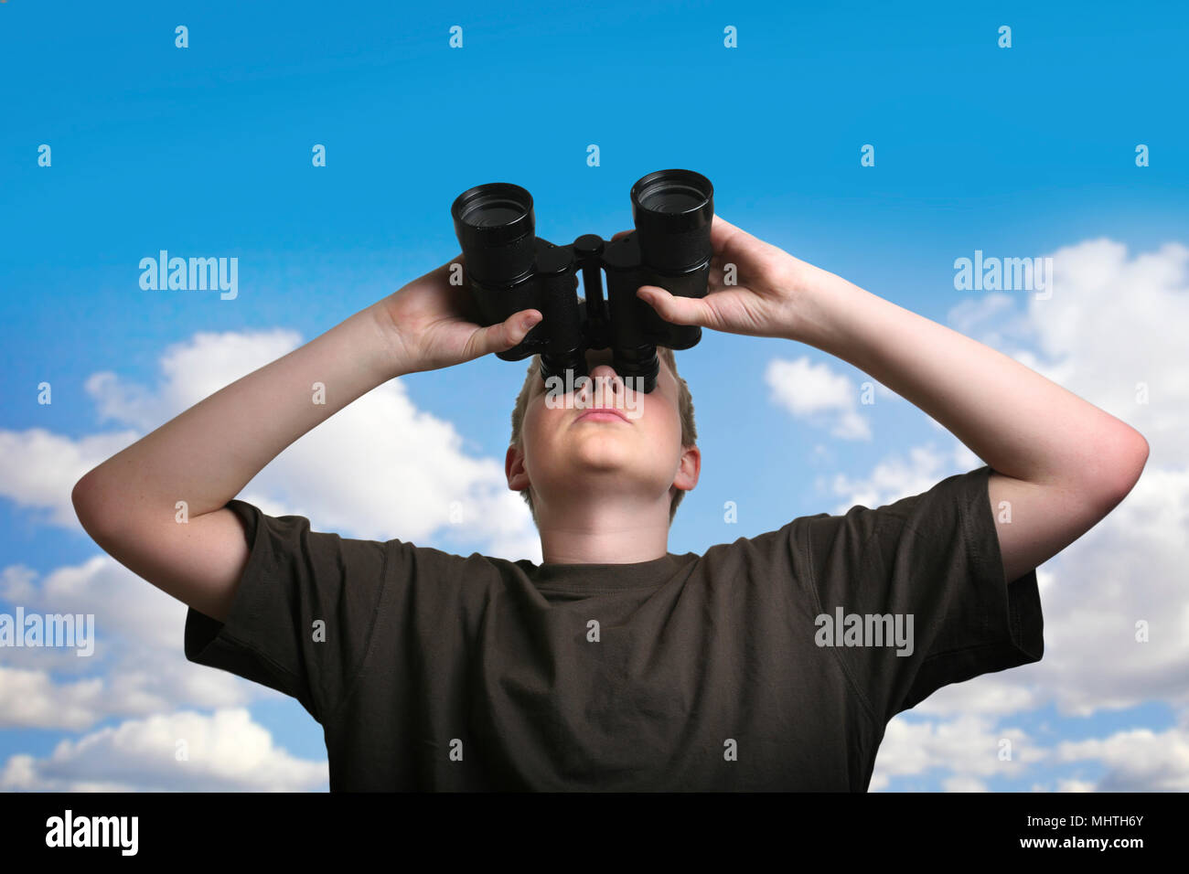 Boy looking through binoculars against sky Stock Photo