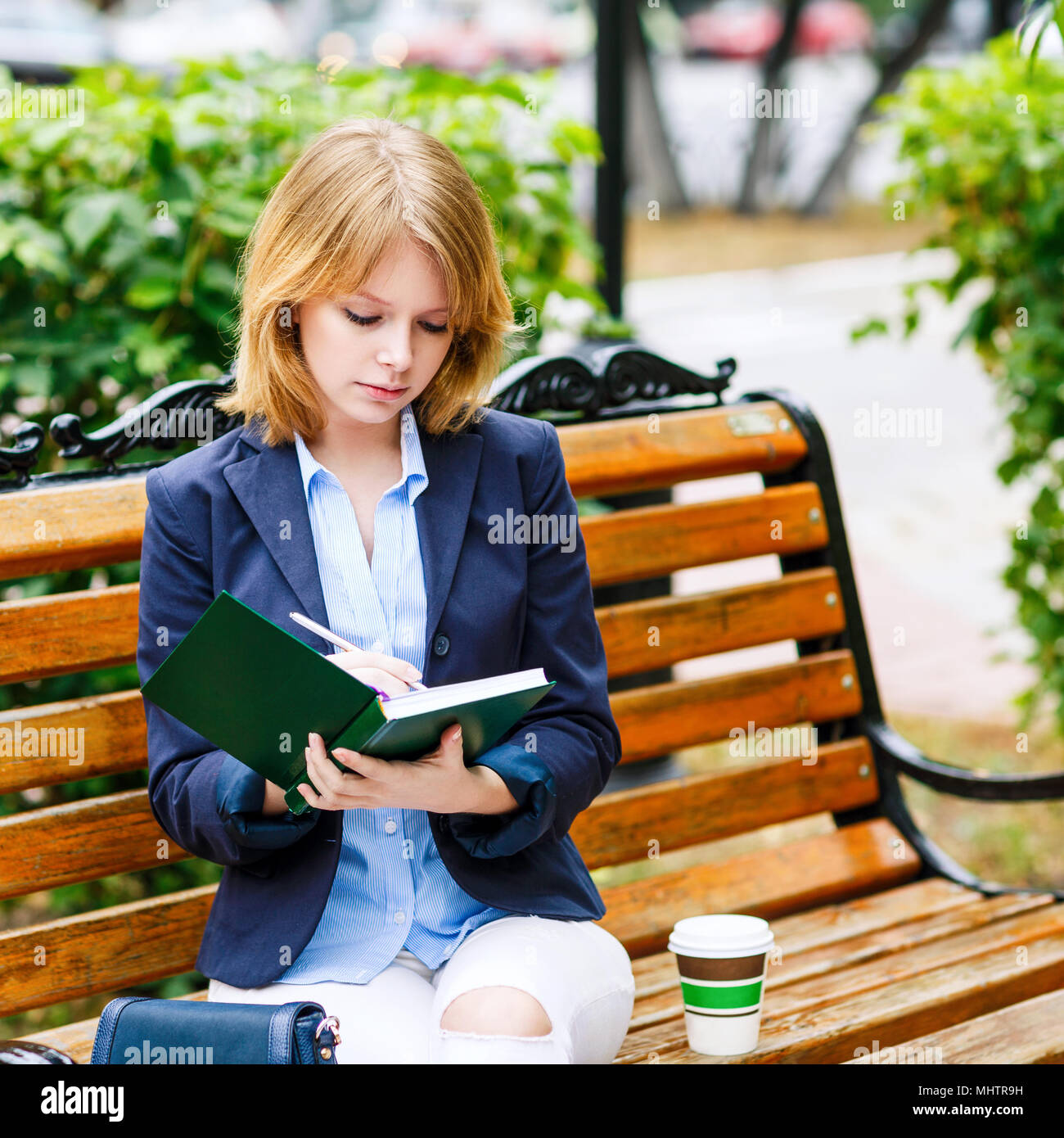 Young woman studying and writing in a park. Stock Photo