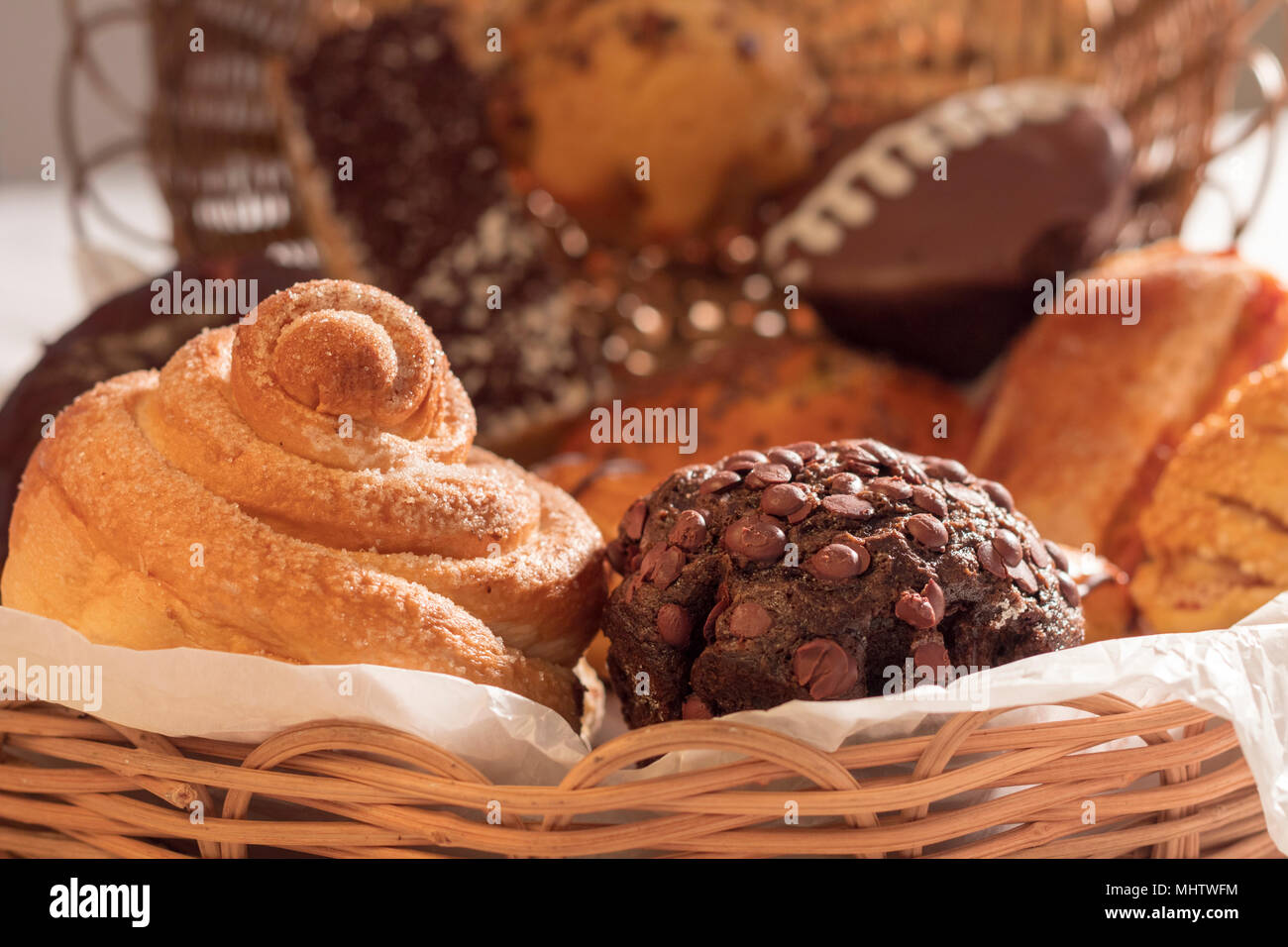 assorted bread for freshly brewed morning coffee and milk on white table cloth and whicker basket. sugary treats full of energy Stock Photo
