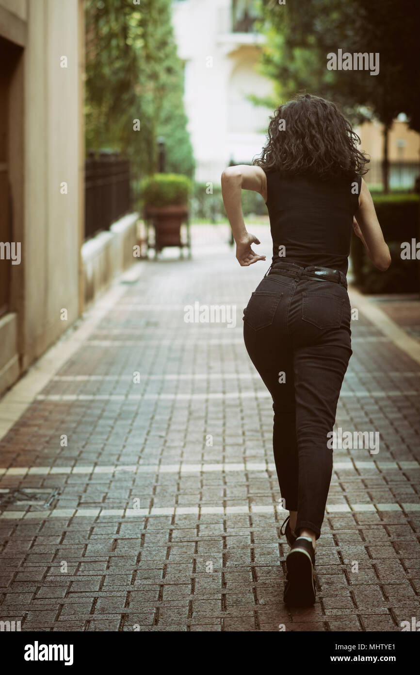 Rear view of a young woman running away Stock Photo