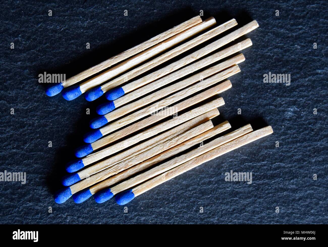 Collection of blue headed matches laid out forming a shape of the letter Z on a black grey slate background. Stock Photo