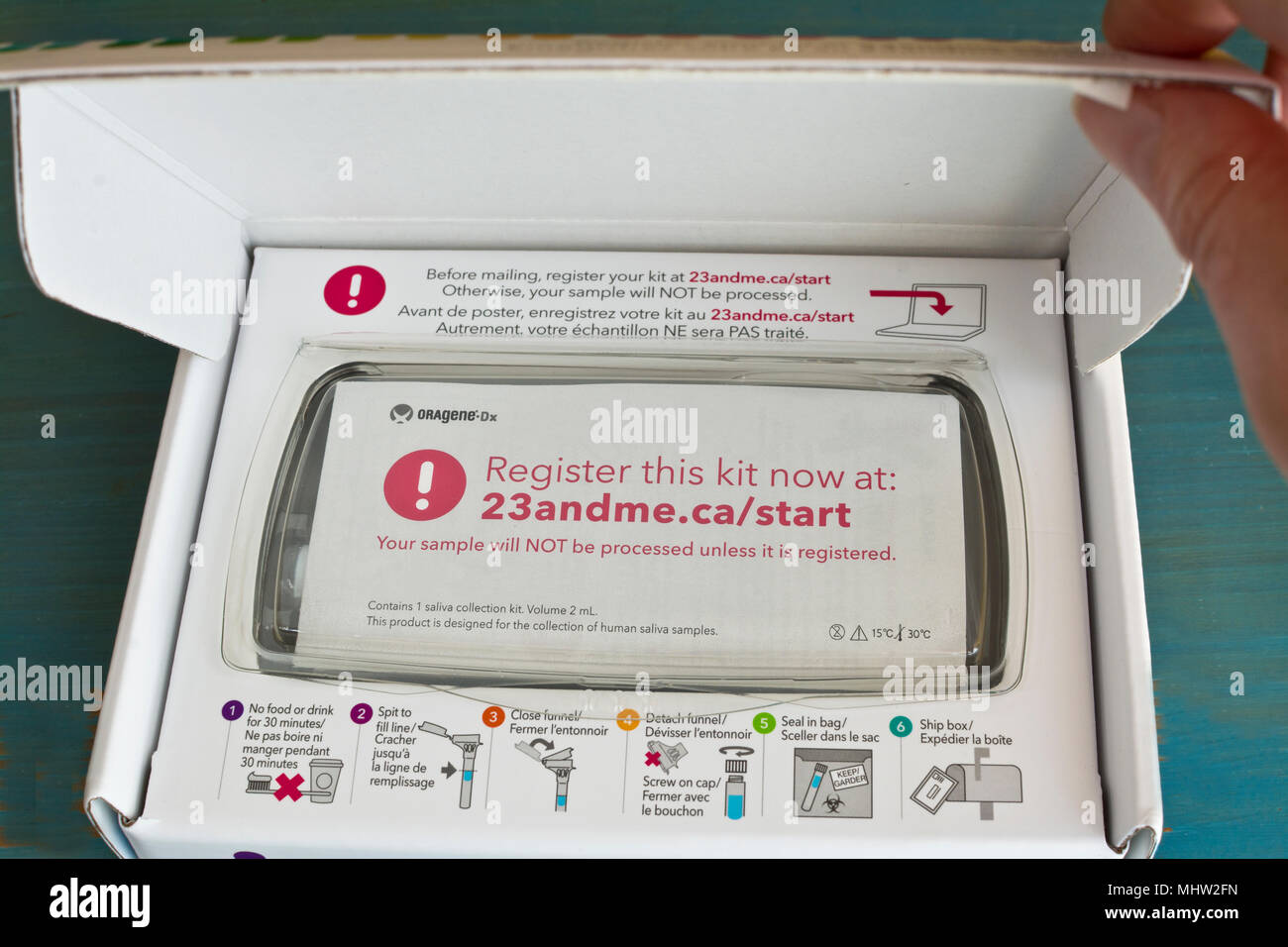 Inside of 23andMe home DNA test kit.  Hand opening box of genetic testing hit. Stock Photo