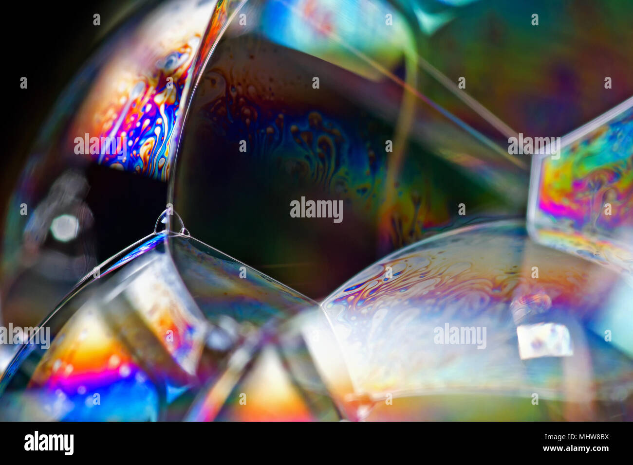 Soap bubbles show the interference of light reflecting off the surfaces of the thin soap film in rainbow patterns. Stock Photo