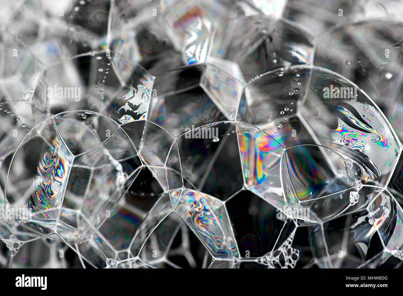 Soap bubbles show the interference of light reflecting off the surfaces of the thin soap film in rainbow patterns. Stock Photo