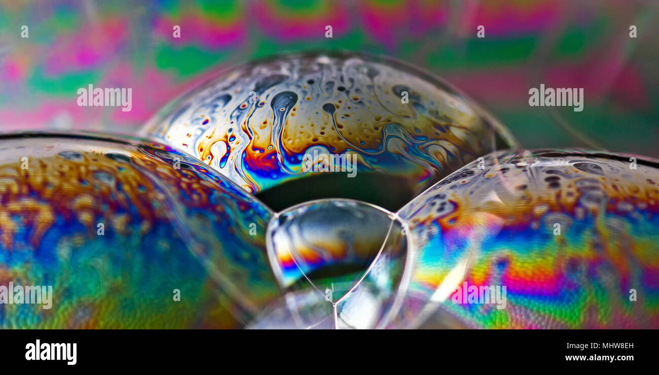 Soap bubbles show the interference of light reflecting off the surfaces of the thin soap film in rainbow patterns. Stock Photo