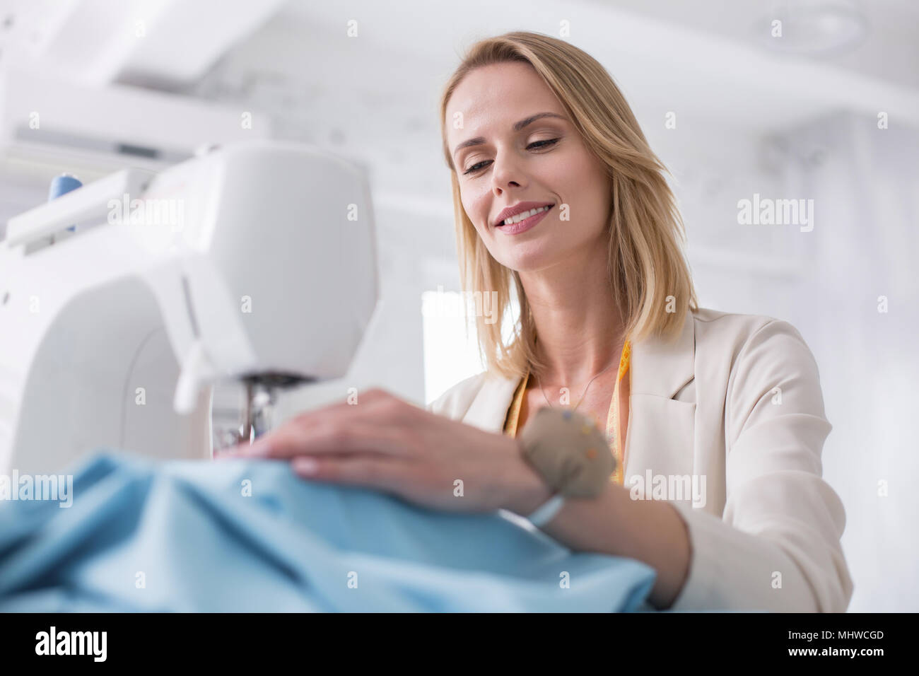 Happy female tailor stitching fabric Stock Photo