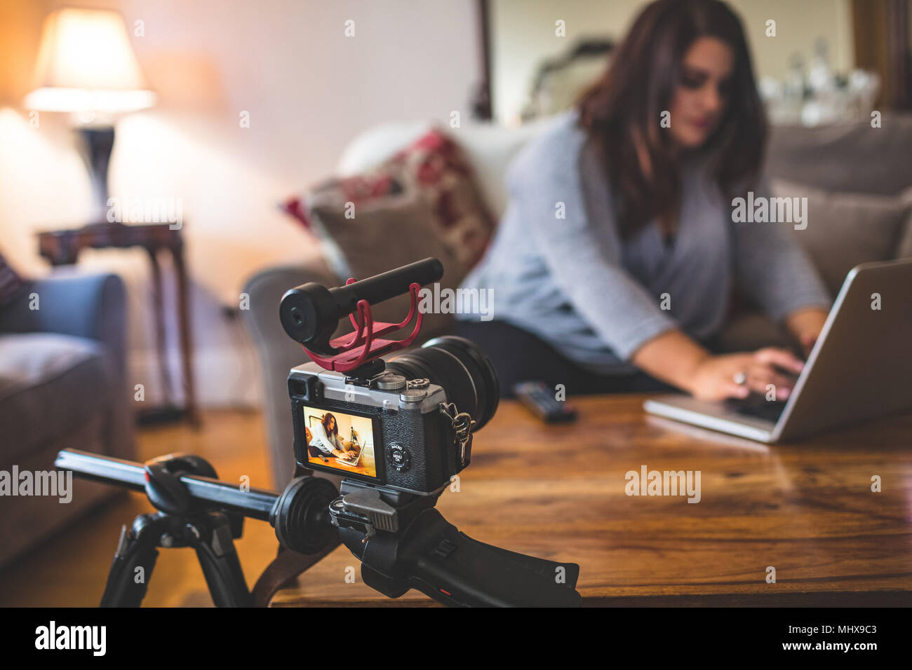 Female vlogger sitting on sofa while using laptop Stock Photo