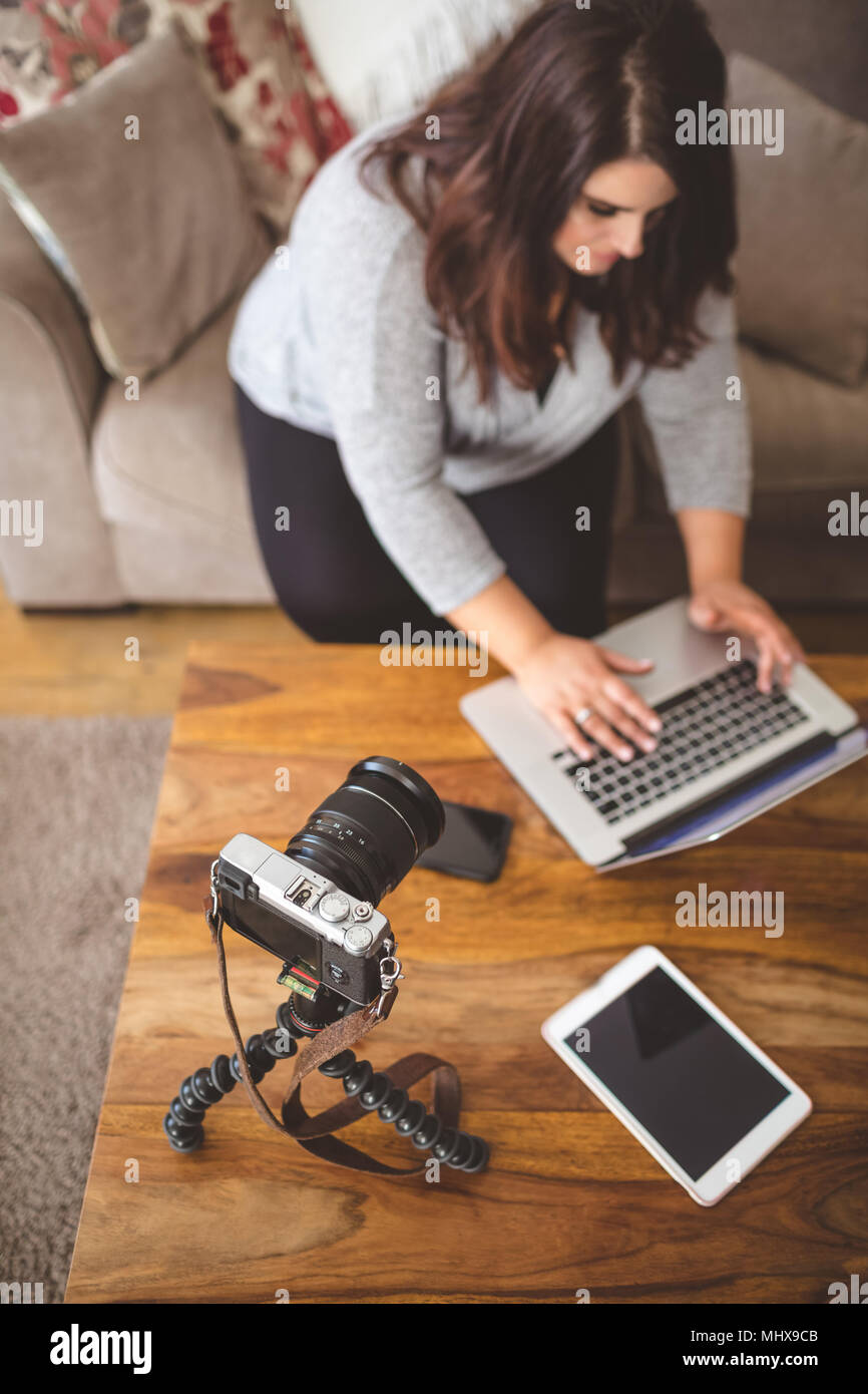 Female vlogger sitting on sofa while using laptop Stock Photo