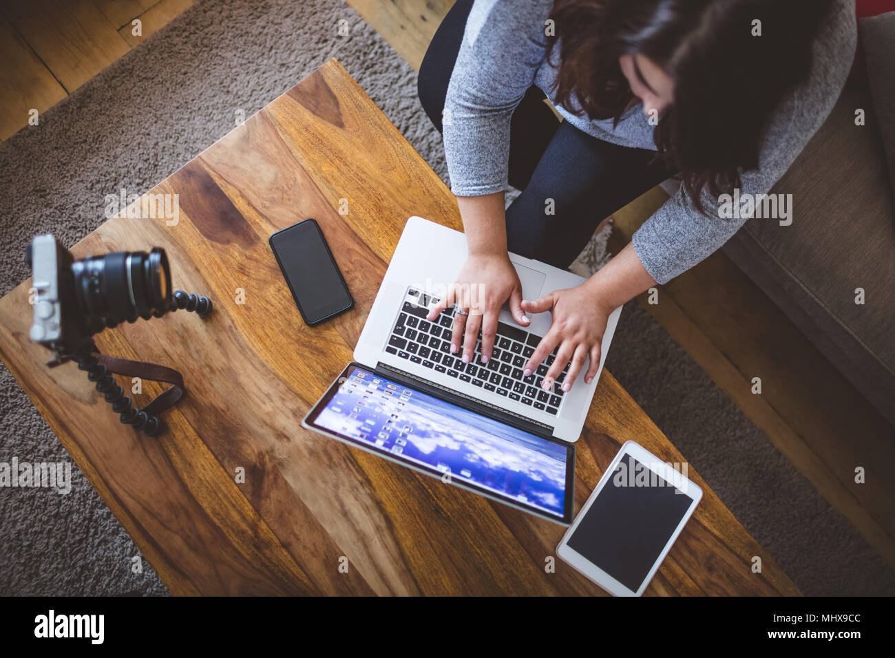 Female vlogger sitting on sofa while using laptop Stock Photo