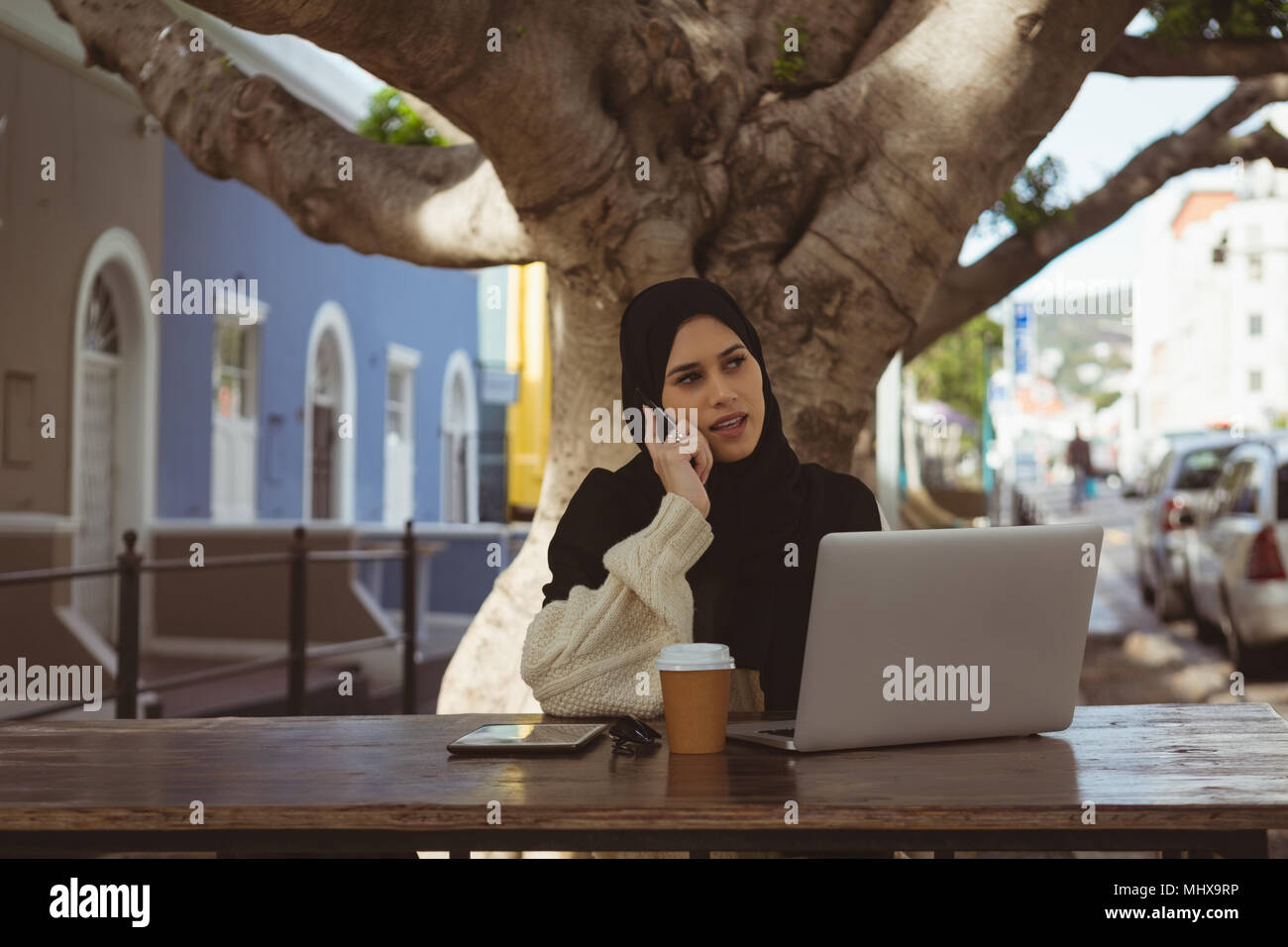 Urban hijab woman talking on mobile phone at cafe Stock Photo