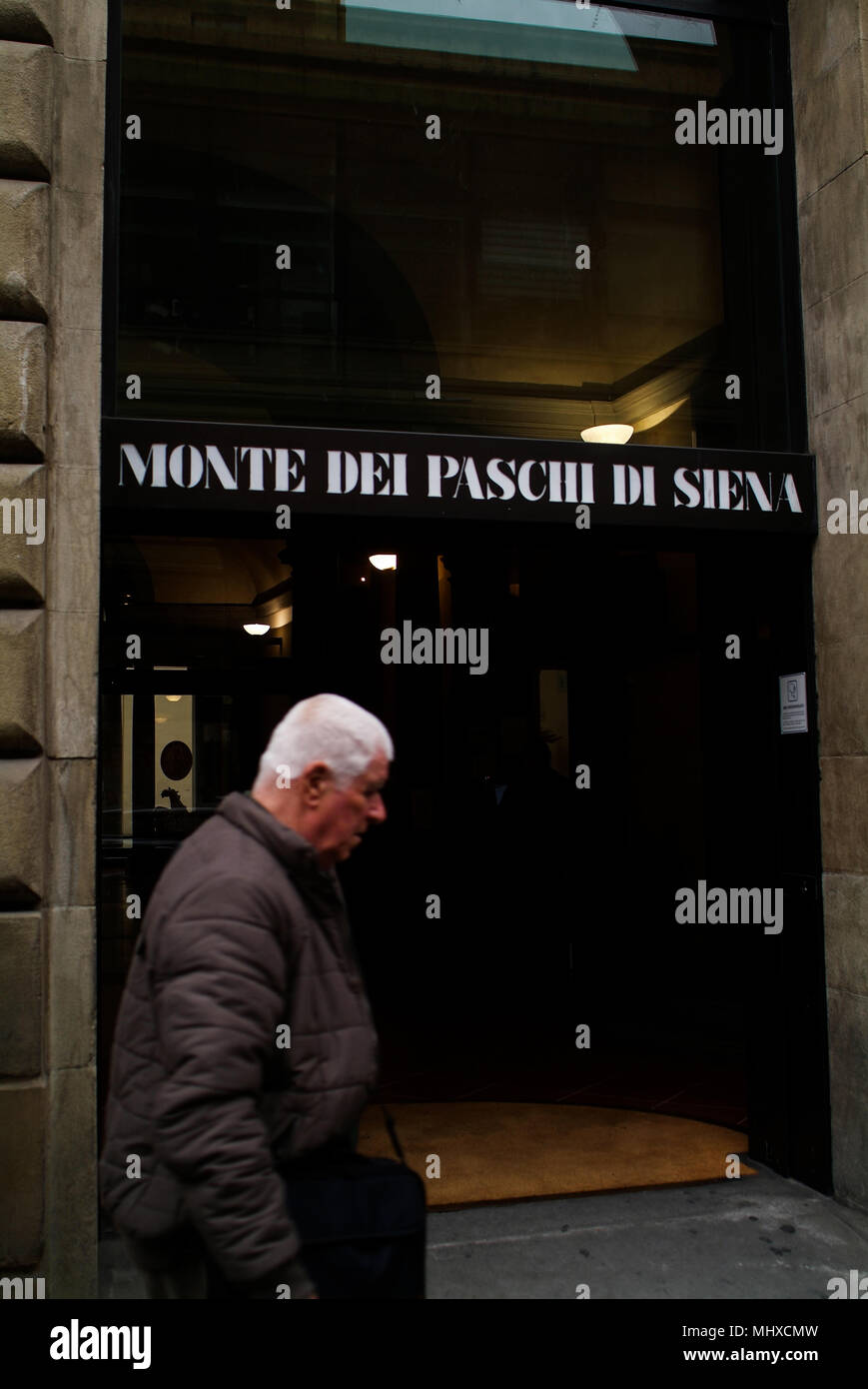 Old man walking in front of a bank of the circuit Monte dei Paschi di Siena, financially collapsed after 2008 bankrupt scandal Stock Photo