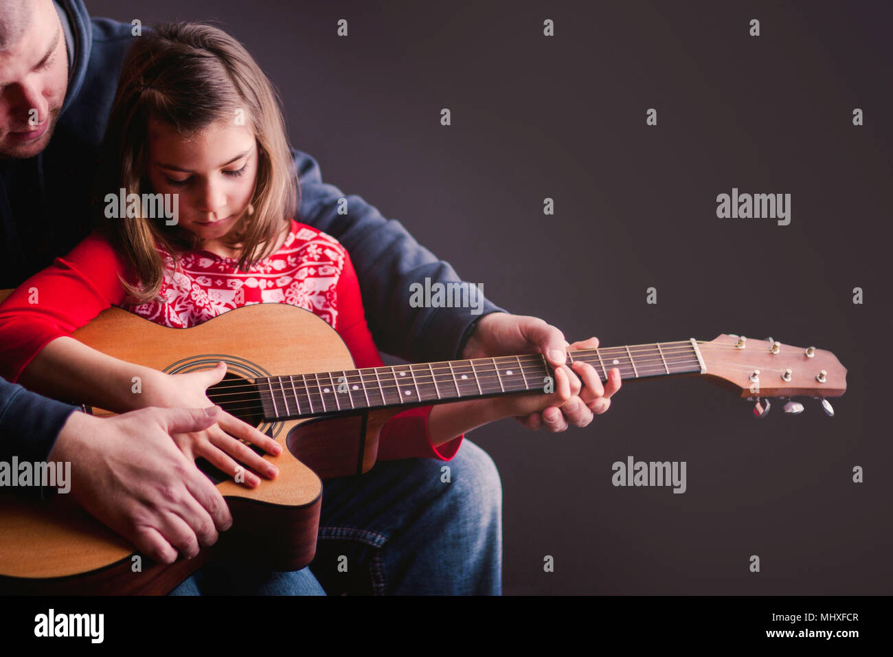Father teaching daughter to play guitar Stock Photo