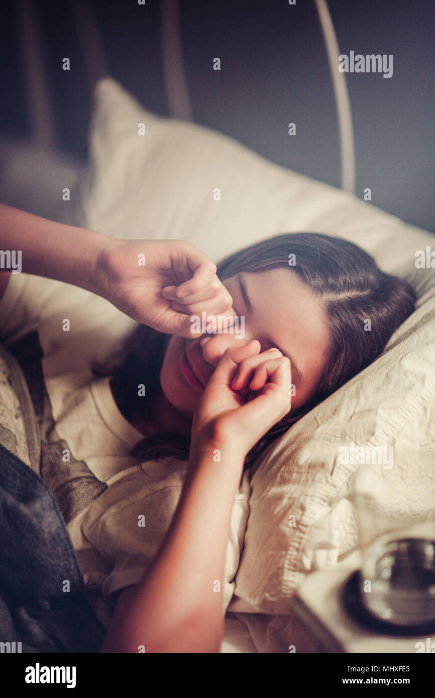 Girl rubbing eyes in bed Stock Photo