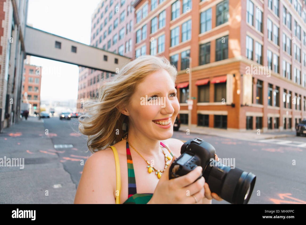 Young woman on city street taking photographs Stock Photo