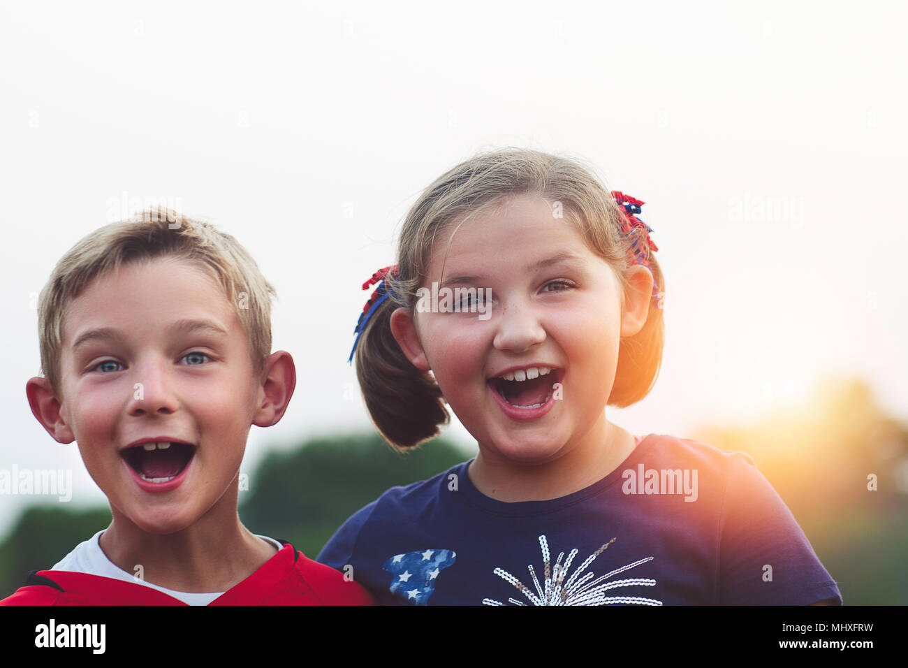 Portrait of boy and girl, mouths open, smiling, looking at camera Stock Photo