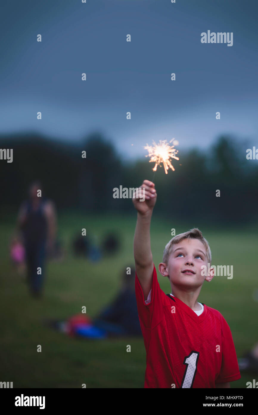Boy with arm raised holding sparkler Stock Photo