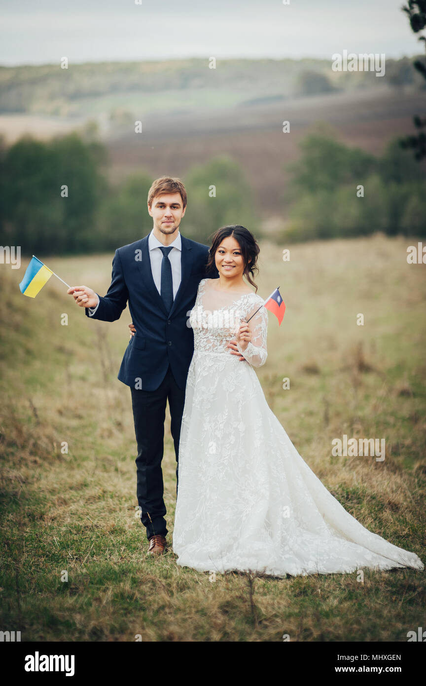 Groom and bride holding flags of Ukraine and Taiwan Stock Photo