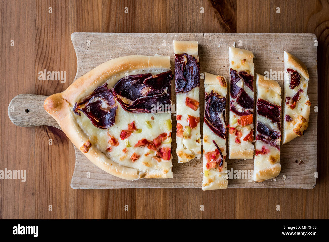Turkish Pide with Pastirma , tomato and melted cheese on a wooden surface. Stock Photo