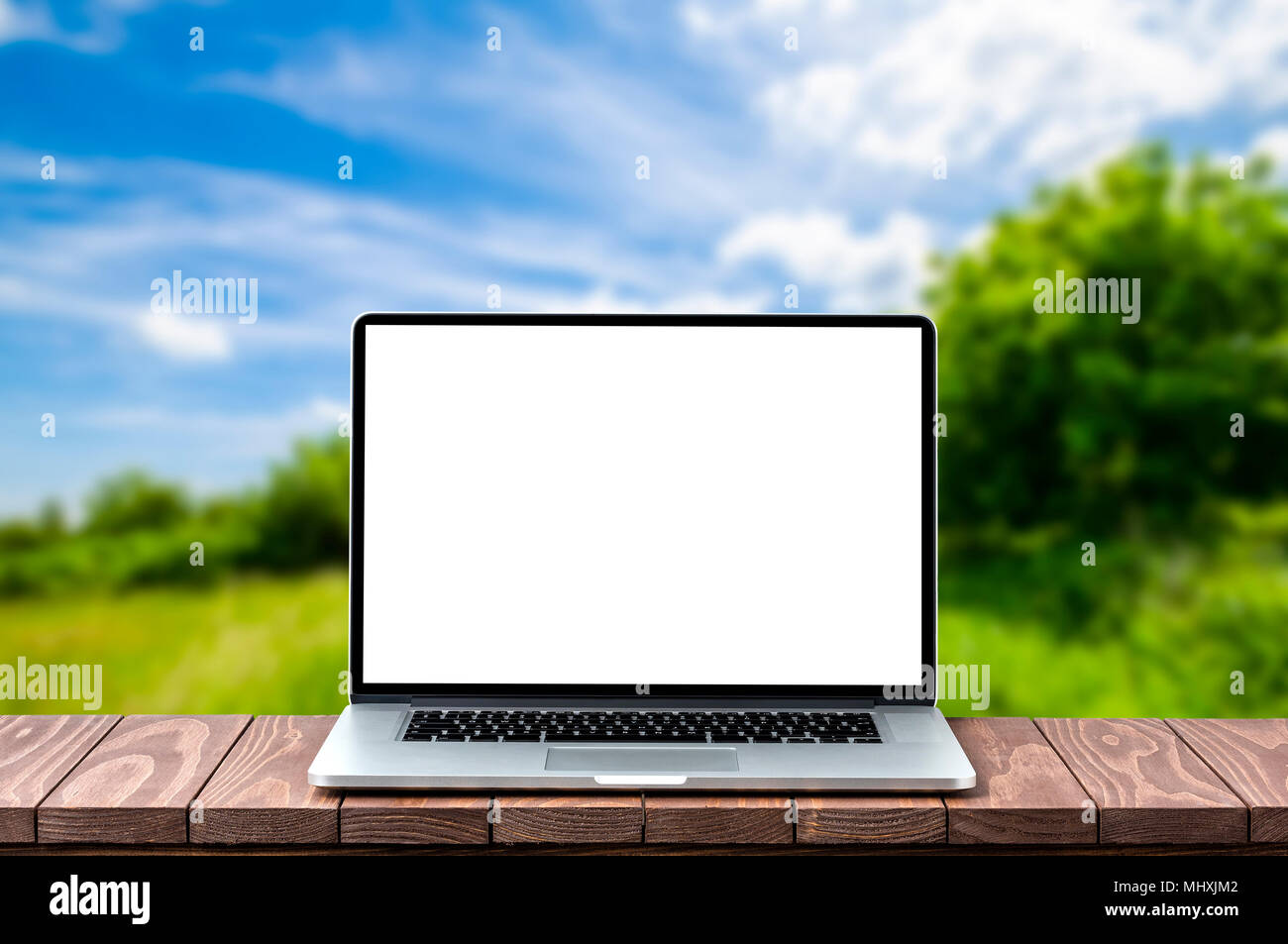 Modern laptop with empty white screen on wooden table against blurred ...